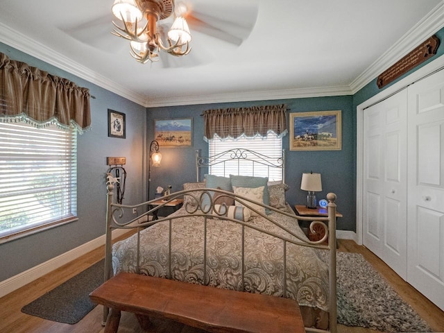 bedroom featuring multiple windows, a closet, ceiling fan with notable chandelier, and hardwood / wood-style flooring