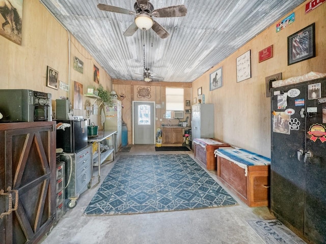 interior space with ceiling fan and wooden walls