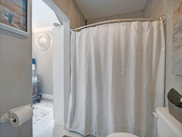 bathroom with tile patterned floors, toilet, and ornamental molding