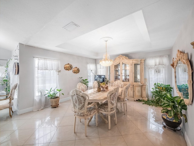 tiled dining room featuring a raised ceiling and an inviting chandelier