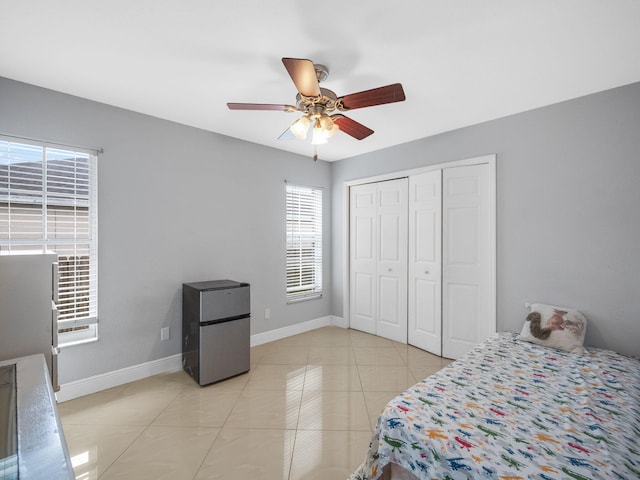 bedroom with fridge, ceiling fan, light tile patterned floors, stainless steel refrigerator, and a closet