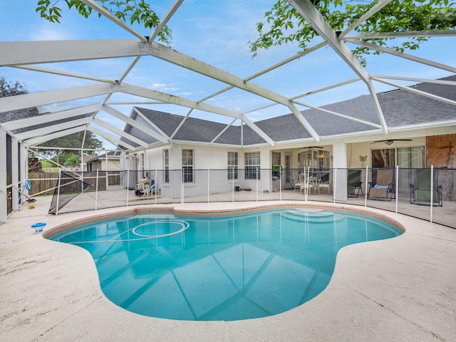 view of pool with glass enclosure, ceiling fan, and a patio area