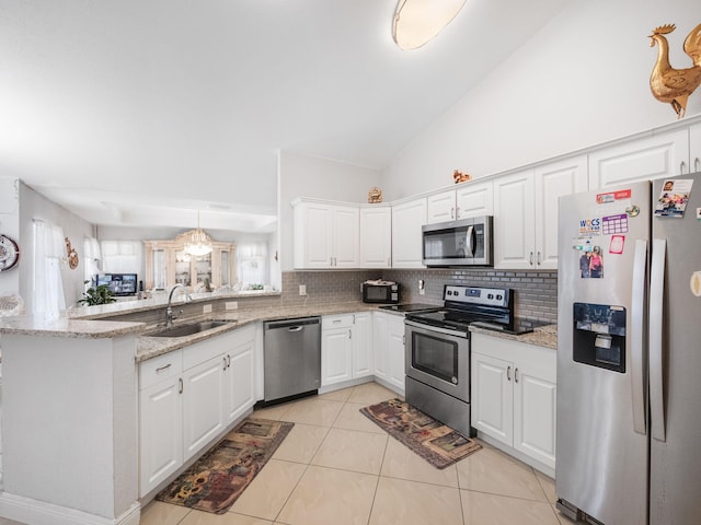 kitchen with white cabinets, sink, light stone counters, kitchen peninsula, and stainless steel appliances