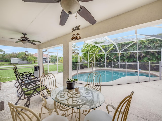 view of pool featuring a yard, glass enclosure, ceiling fan, and a patio area