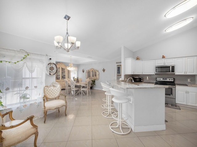 kitchen with pendant lighting, white cabinets, decorative backsplash, stainless steel appliances, and a chandelier