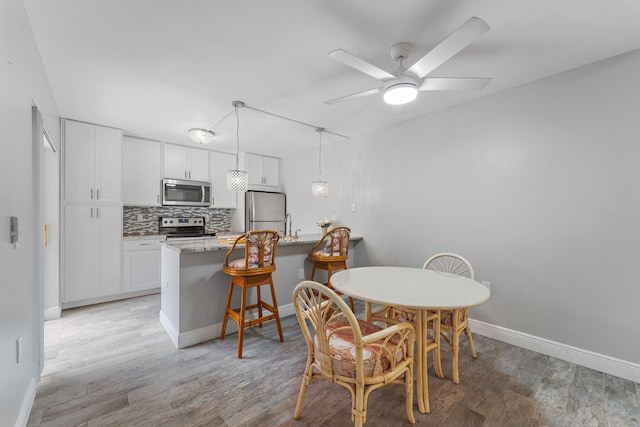 dining area featuring light wood-type flooring and ceiling fan