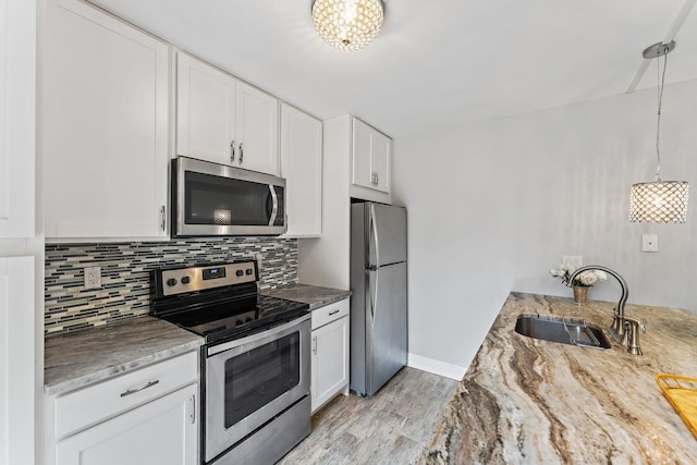 kitchen with decorative light fixtures, white cabinetry, sink, and appliances with stainless steel finishes