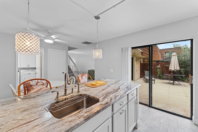 kitchen with white cabinetry, light stone counters, ceiling fan, and hanging light fixtures