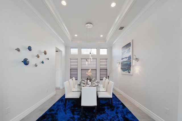 dining space featuring dark tile patterned floors, crown molding, and a tray ceiling