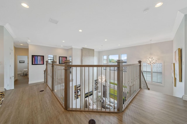 hall with an inviting chandelier, light hardwood / wood-style flooring, and ornamental molding