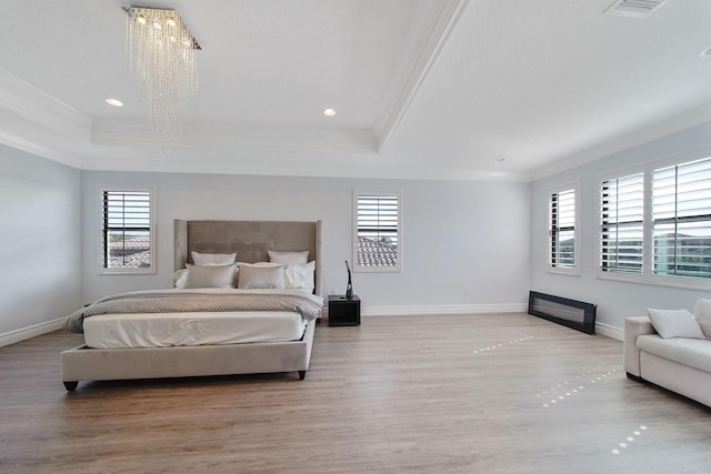 bedroom with a tray ceiling, an inviting chandelier, and multiple windows