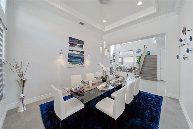 dining space featuring a chandelier, a raised ceiling, and ornamental molding