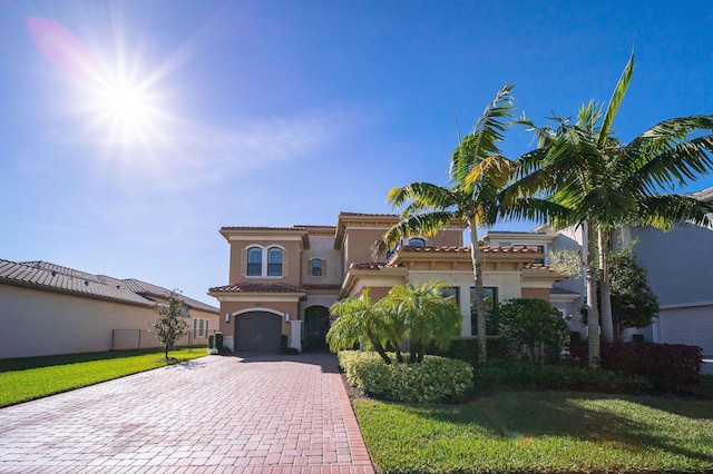 mediterranean / spanish-style house featuring a garage and a front lawn