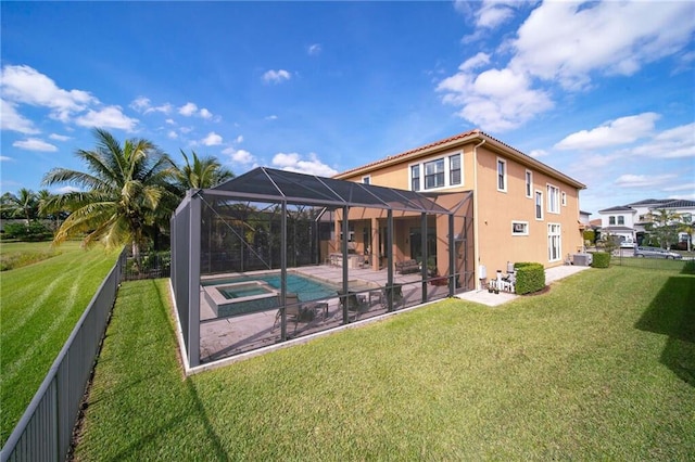 rear view of house with a lawn, glass enclosure, a patio area, and a swimming pool with hot tub