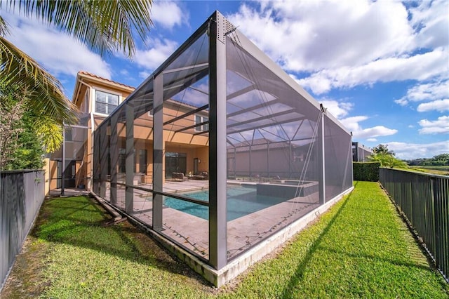 back of house featuring a pool with hot tub, glass enclosure, and a lawn