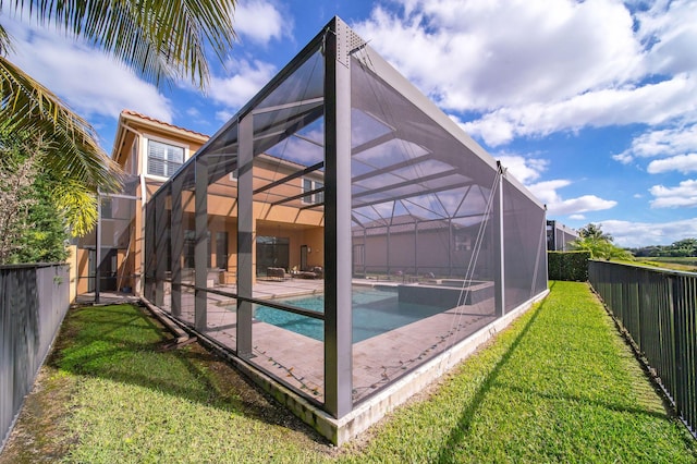 rear view of property featuring a swimming pool with hot tub, a yard, and glass enclosure