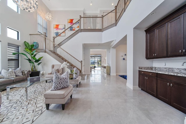 interior space with ornamental molding, sink, a towering ceiling, and an inviting chandelier