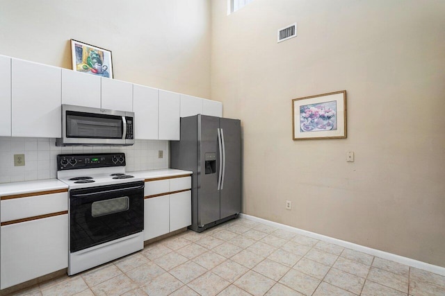 kitchen with light tile patterned floors, a towering ceiling, decorative backsplash, white cabinets, and appliances with stainless steel finishes