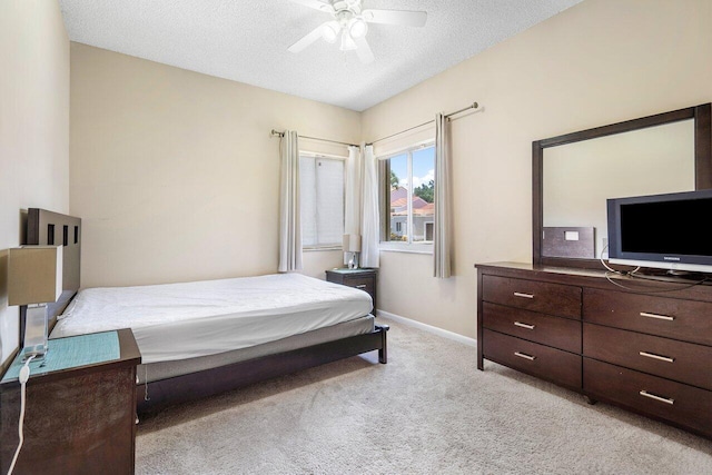 carpeted bedroom with ceiling fan and a textured ceiling