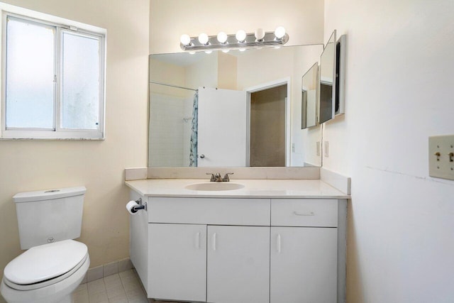 bathroom with tile patterned floors, a wealth of natural light, vanity, and toilet