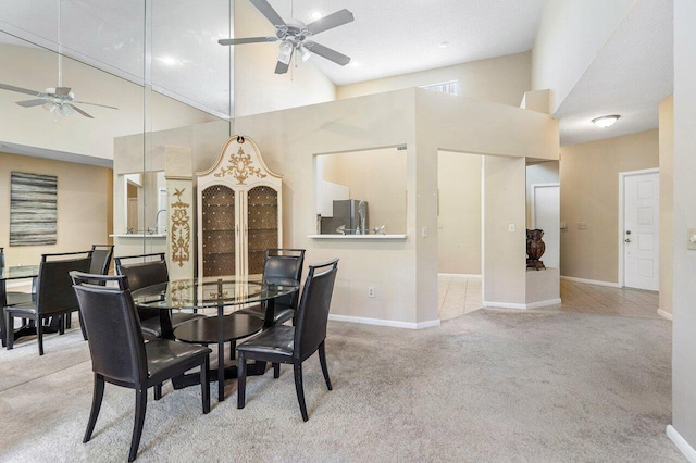 carpeted dining room with ceiling fan and a high ceiling