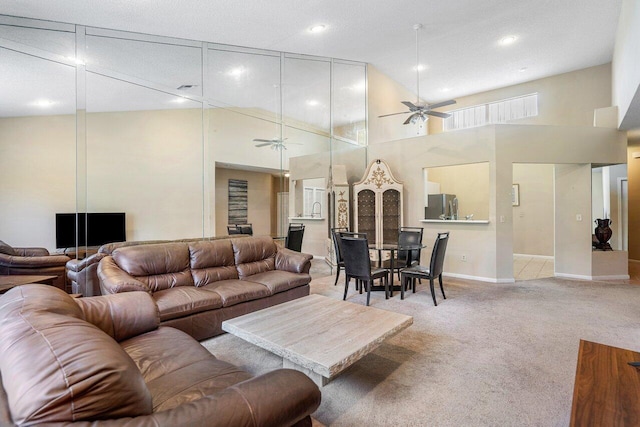 living room featuring ceiling fan, sink, a high ceiling, a textured ceiling, and light carpet