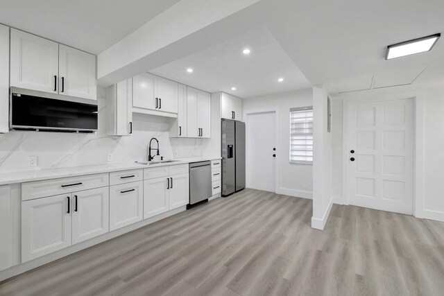 kitchen with sink, appliances with stainless steel finishes, white cabinetry, tasteful backsplash, and island exhaust hood