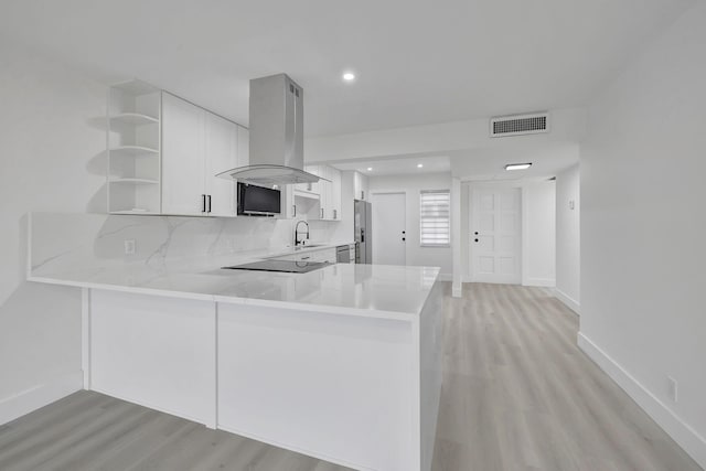 kitchen with white cabinetry, sink, island exhaust hood, kitchen peninsula, and stainless steel refrigerator with ice dispenser