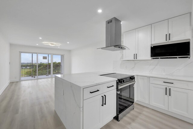 kitchen with light stone counters, island range hood, white cabinets, and light wood-type flooring