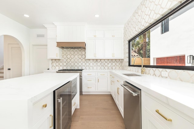 kitchen featuring stainless steel appliances, beverage cooler, sink, light hardwood / wood-style floors, and white cabinetry