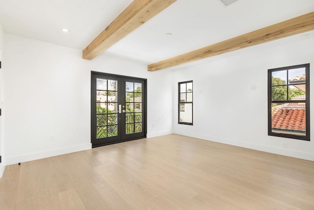 empty room with beamed ceiling, french doors, and light hardwood / wood-style floors