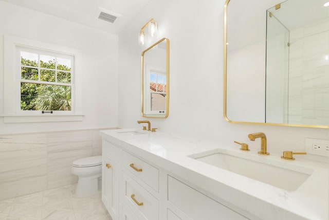 bathroom with vanity, tile walls, and toilet