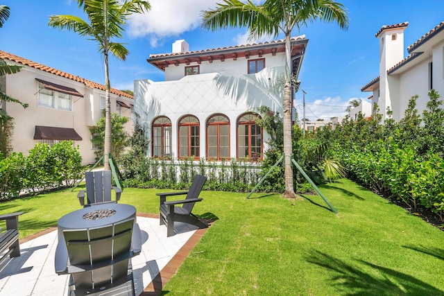 back of house with a patio, a yard, and a fire pit