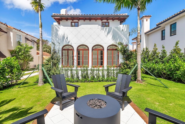 back of house with a yard, a patio, and an outdoor fire pit