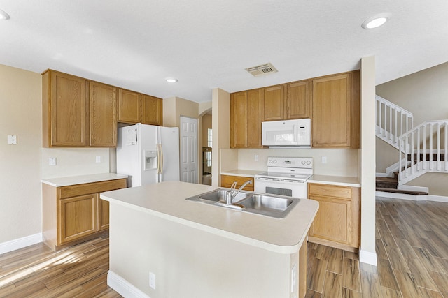 kitchen with white appliances, a kitchen island with sink, and sink