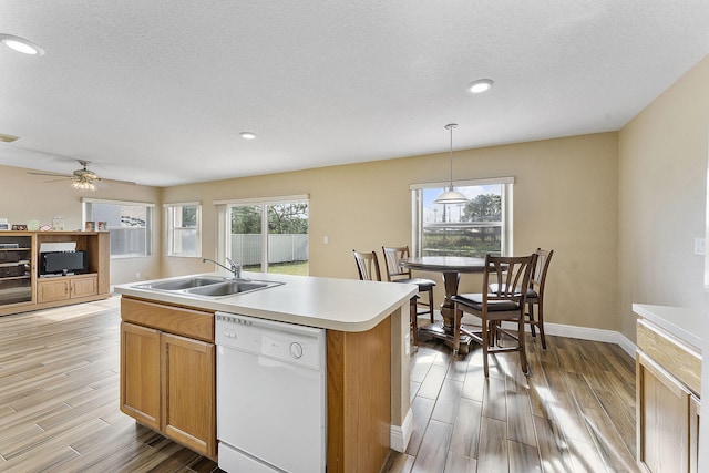 kitchen with dishwasher, a kitchen island with sink, sink, hanging light fixtures, and ceiling fan