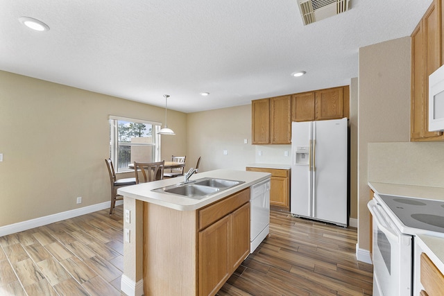 kitchen featuring sink, decorative light fixtures, white appliances, a kitchen island with sink, and hardwood / wood-style flooring