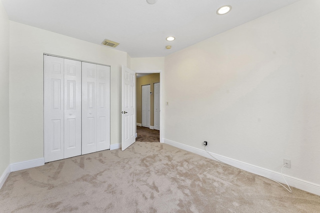 unfurnished bedroom featuring light carpet and a closet