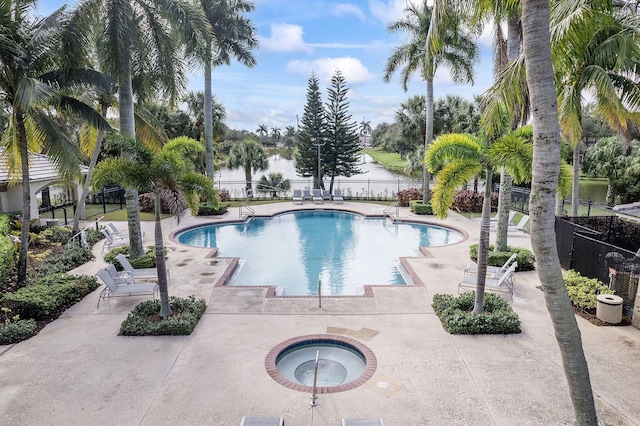 view of pool with a patio area, a water view, and a hot tub