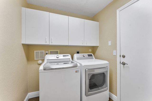 laundry room featuring separate washer and dryer and cabinets