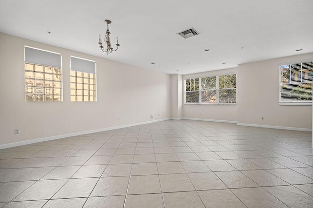 tiled empty room featuring a chandelier