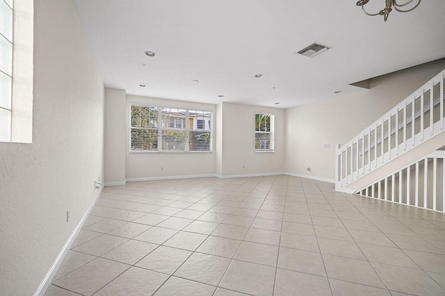 tiled empty room featuring a chandelier