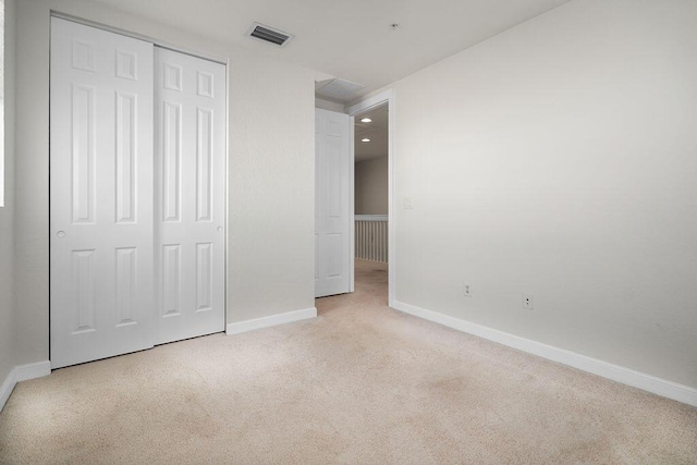 unfurnished bedroom featuring light colored carpet and a closet