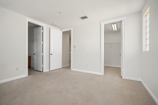 unfurnished bedroom featuring light carpet, a spacious closet, and a closet