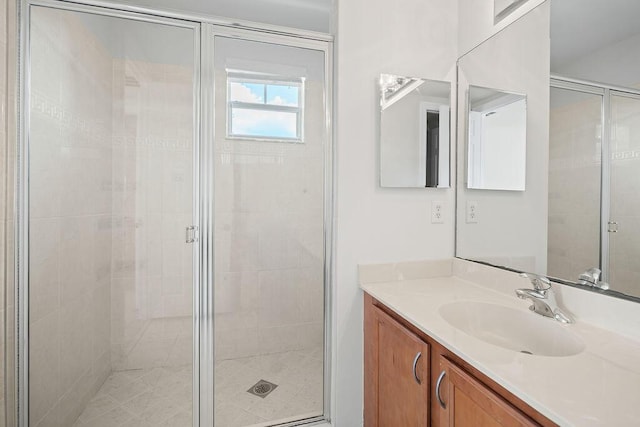 bathroom featuring a shower with door and vanity