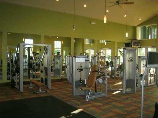 gym with ceiling fan and high vaulted ceiling