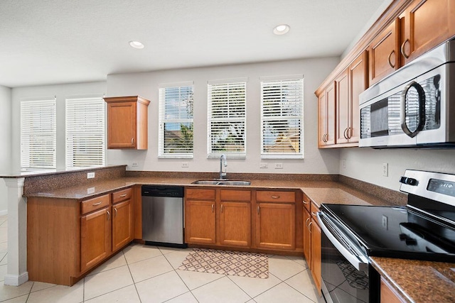 kitchen with kitchen peninsula, sink, light tile patterned floors, and stainless steel appliances