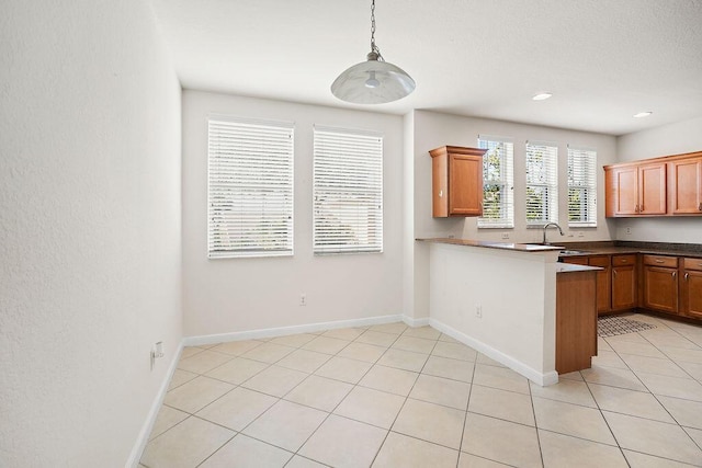 kitchen featuring kitchen peninsula, light tile patterned floors, hanging light fixtures, and sink