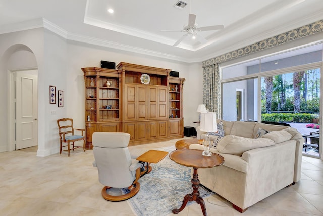 tiled living room featuring a raised ceiling, ceiling fan, and ornamental molding