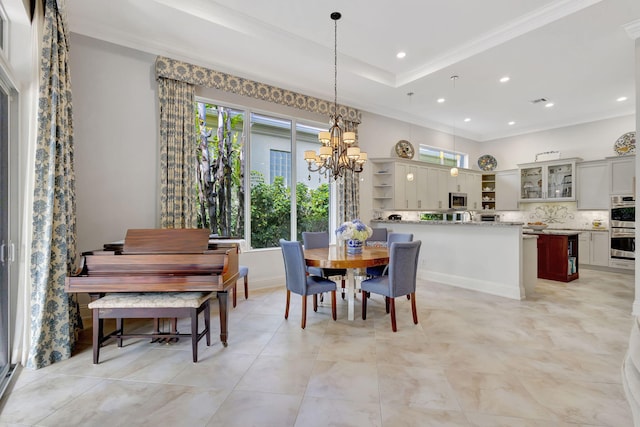 dining area featuring a raised ceiling, crown molding, and a chandelier